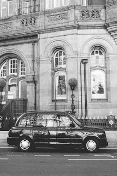 Black taxi parked in front of historic building in Manchester, UK.