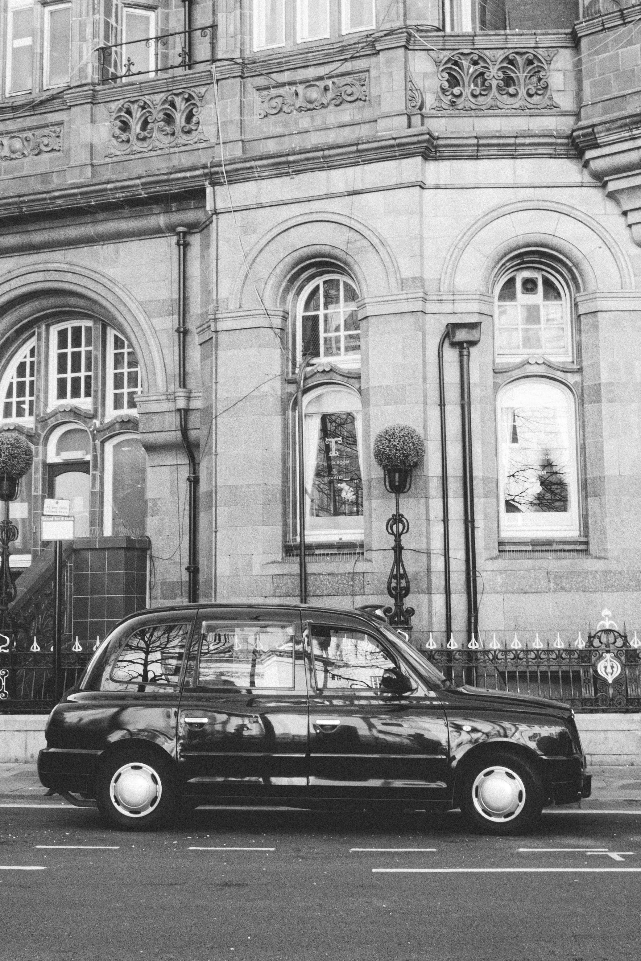 Ücretsiz İngiltere'nin Manchester şehrinde tarihi bir binanın önünde park halinde duran siyah taksi. Stok Fotoğraflar