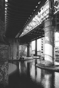 A moody black and white photo of a canal bridge in Manchester, UK.