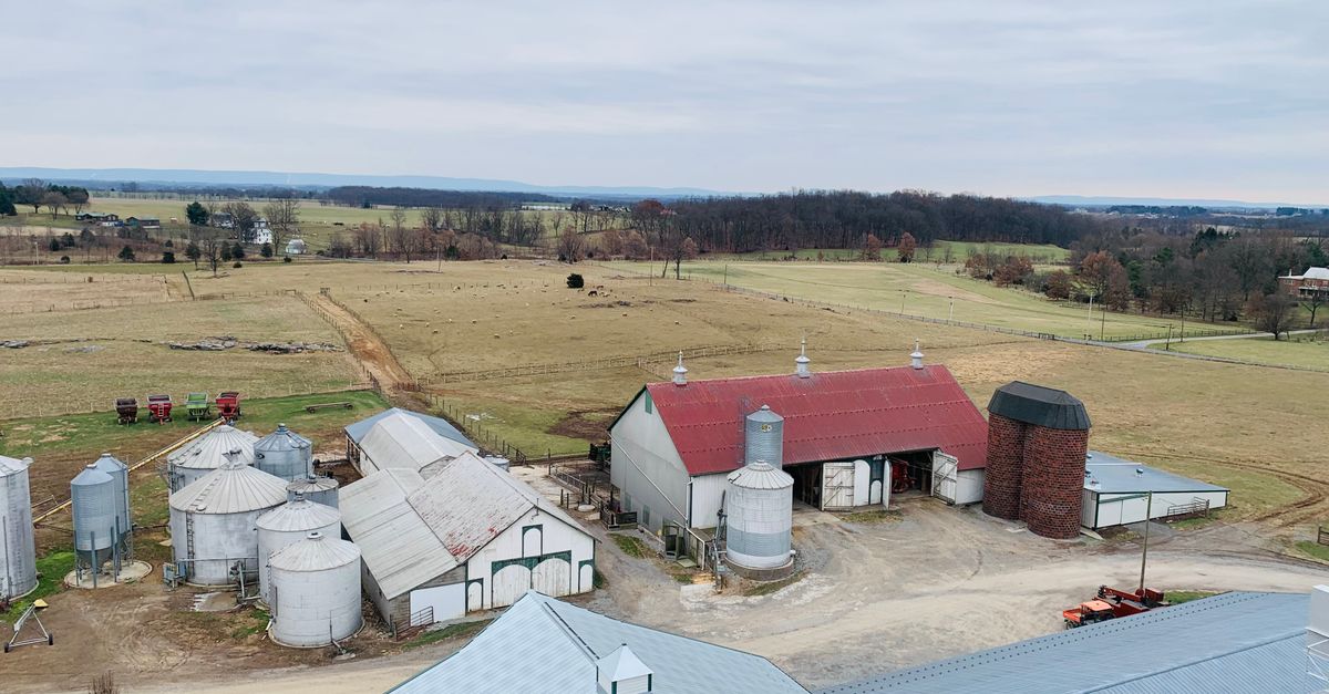 Aerial view of a Maryland farm with barns and silos under a cloudy sky.