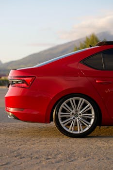 Stylish red sedan rear against mountain backdrop, showcasing design and landscape.