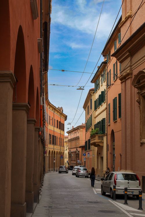 Free Explore a picturesque street in Bologna, Italy, showcasing traditional Italian architecture under a vibrant sky. Stock Photo