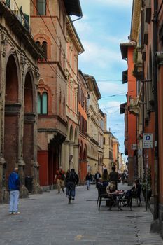 A vibrant street in Bologna, Italy, showcasing historic architecture and bustling activity.