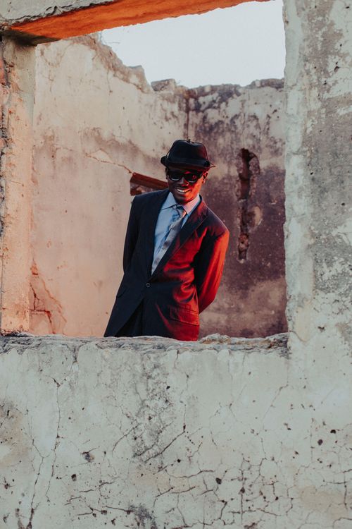 Free A man in a suit and hat stands in aged ruins amid the warm sunset. Stock Photo