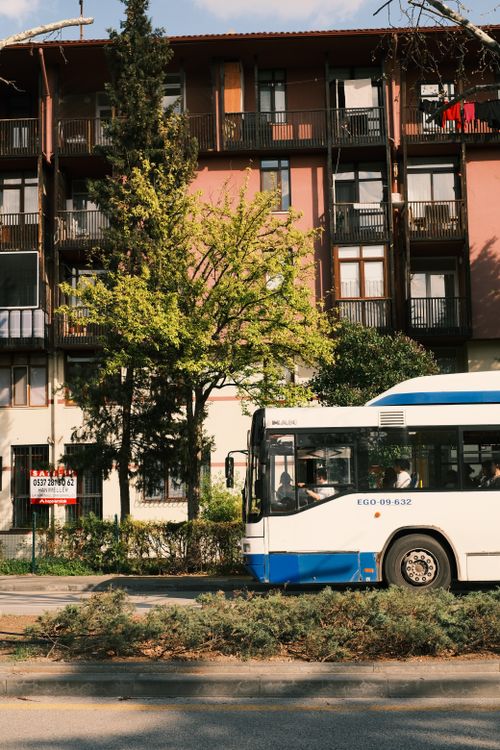 Free A city bus travels beside an urban residential building covered in plants. Stock Photo