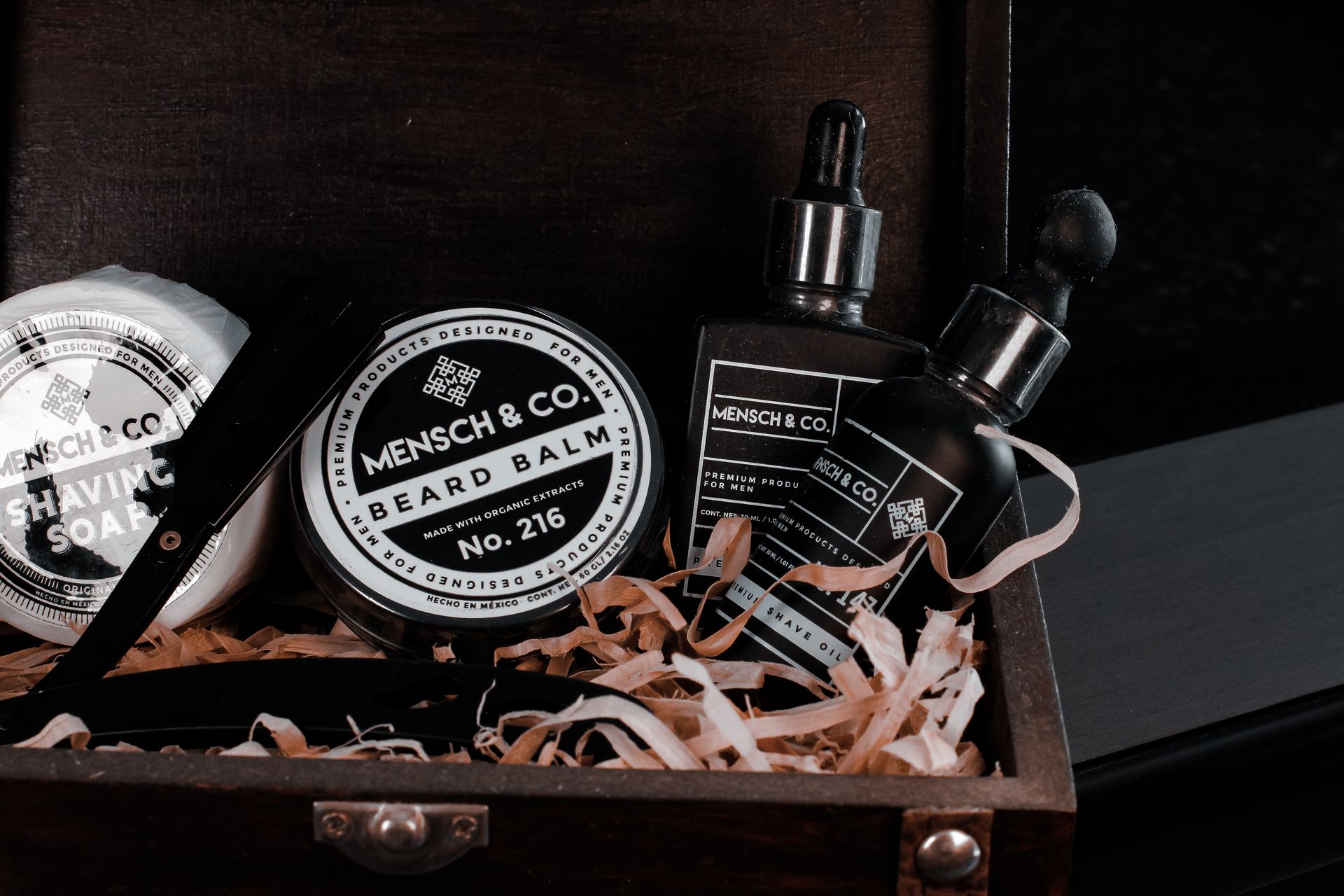 Elegant collection of traditional men's grooming products in a stylish wooden box featuring beard balm, shave oil, and shaving soap.