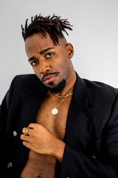 Portrait of a confident young man wearing a black blazer and gold jewelry.
