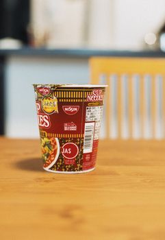 Cup of Nissin instant noodles on a wooden table, showcasing popular Japanese fast food.