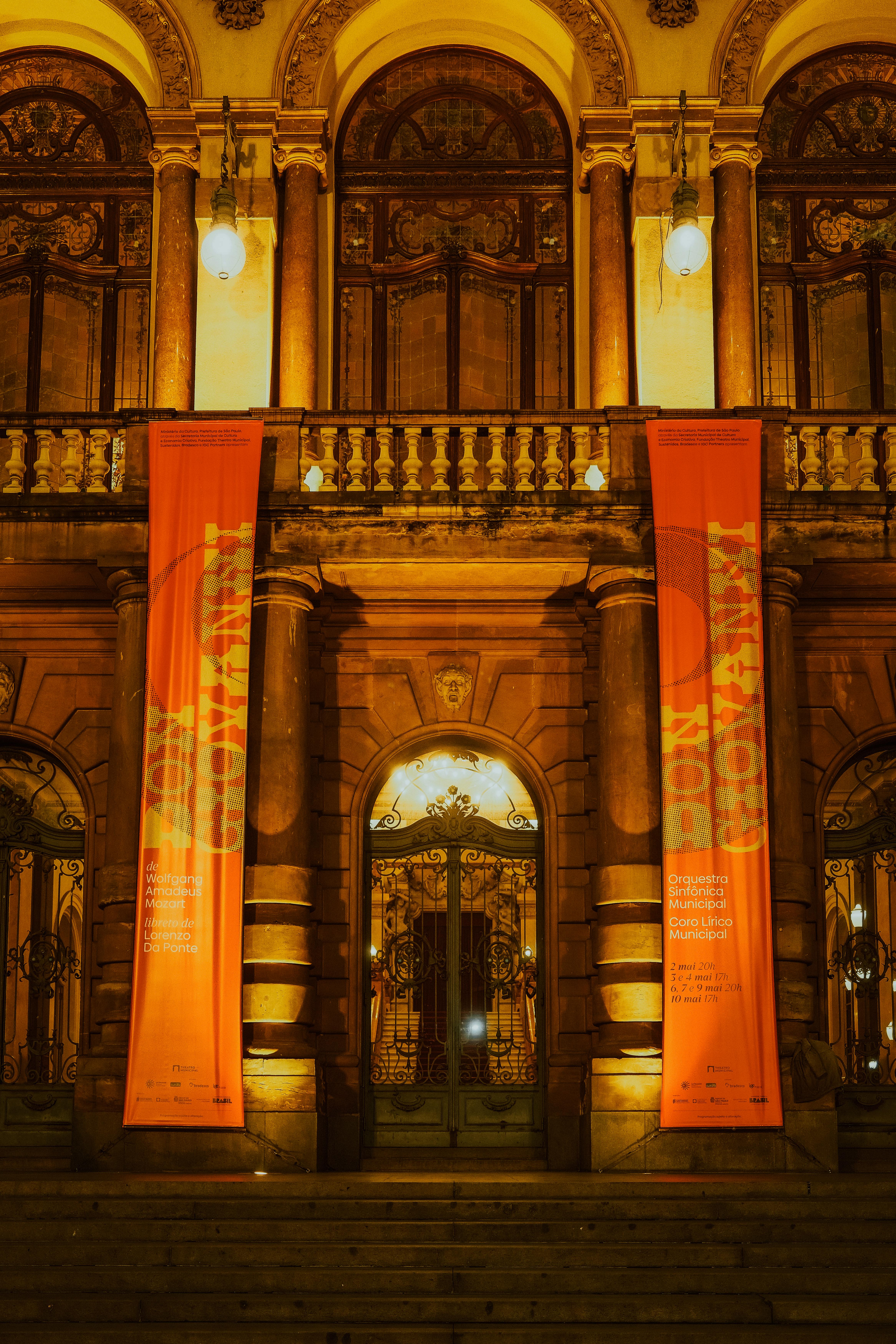 Gratis Theatro Municipal de São Paulo opplyst om natten med fargerike bannere som viser frem kulturelle begivenheter. Arkivbilde