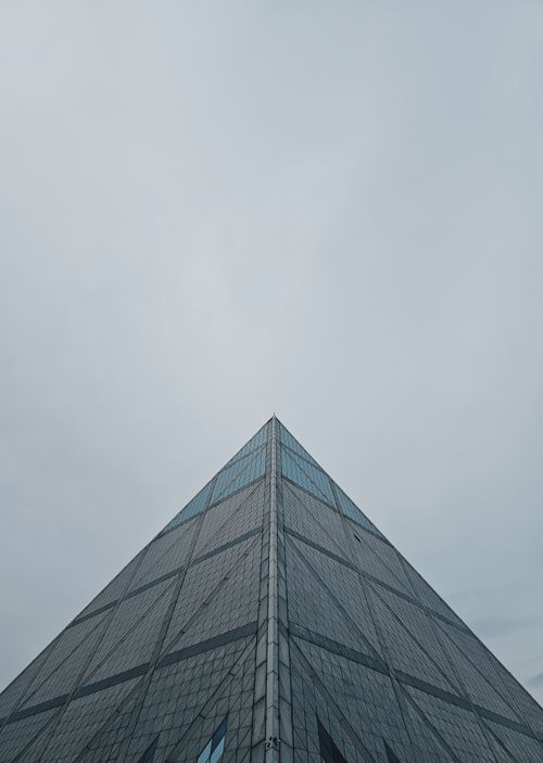 Free A striking view of a modern pyramid-like building with cloudy sky creating a dramatic atmosphere. Stock Photo