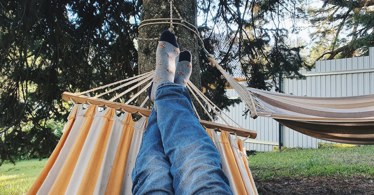 Person in jeans relaxing on hammock in sunny backyard, creating a cozy outdoor vibe.