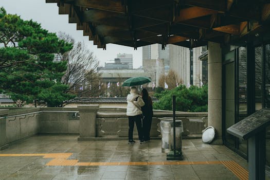 A candid street photo capturing two people under an umbrella during a rainy day in Seoul, South Korea.