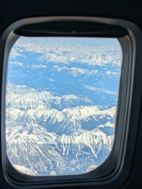 A breathtaking aerial view of snow-covered mountains seen from an airplane window.