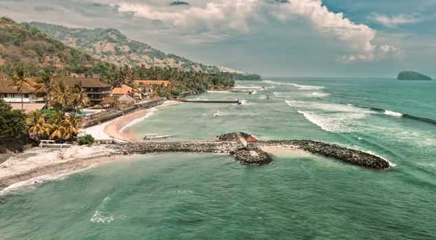 A breathtaking aerial view of a coastal landscape in Bali, showcasing clear waters and lush hills.