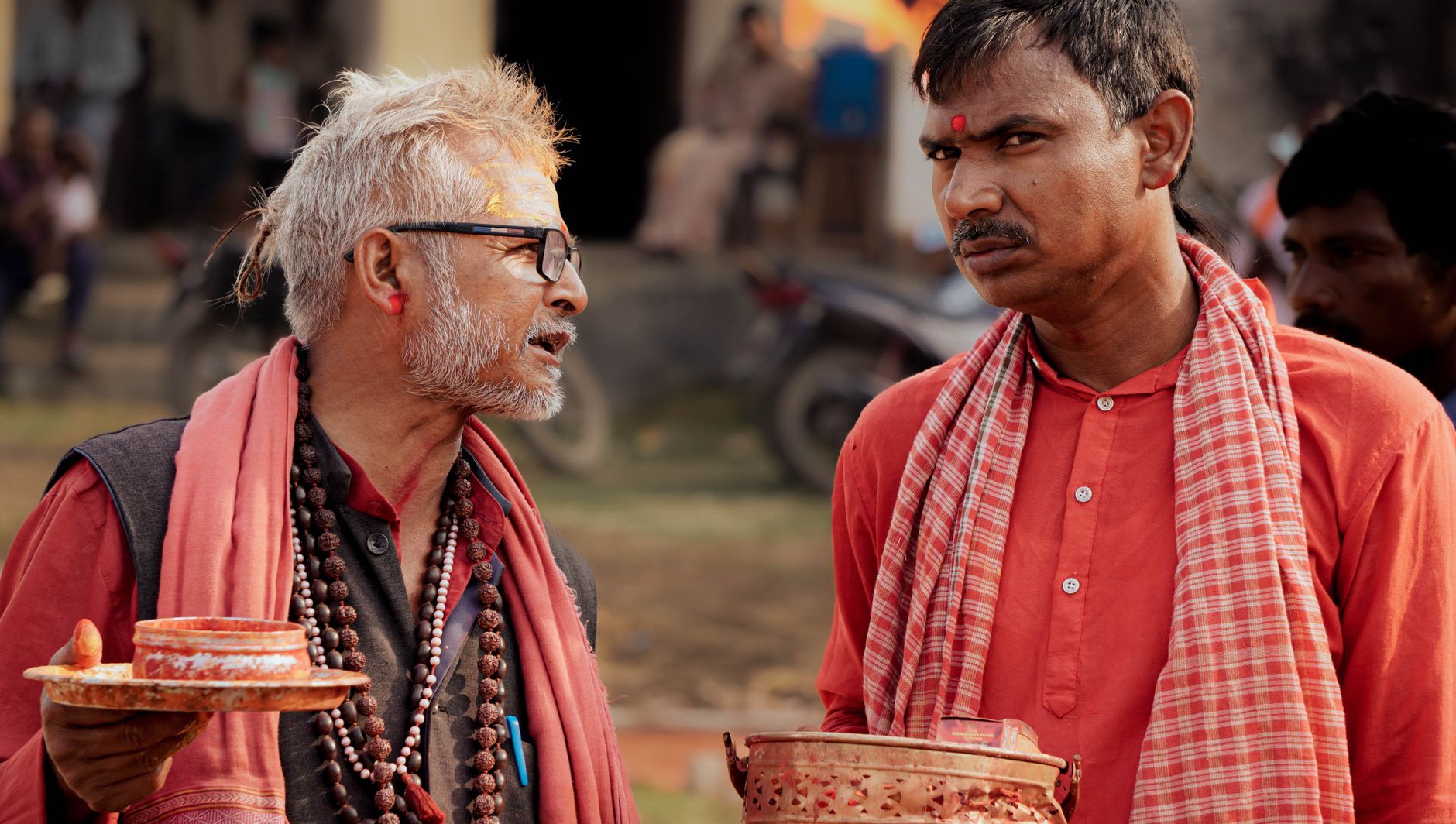 Two men in traditional attire engaged in a Hindu ritual in Patna, India, holding ceremonial items.