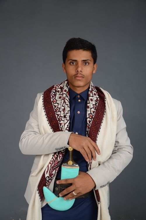 Free Portrait of a young man wearing culturally significant Middle Eastern clothing holding a decorative dagger. Stock Photo