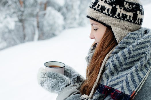 Woman in winter attire holding a hot beverage outdoors in snowy surroundings.