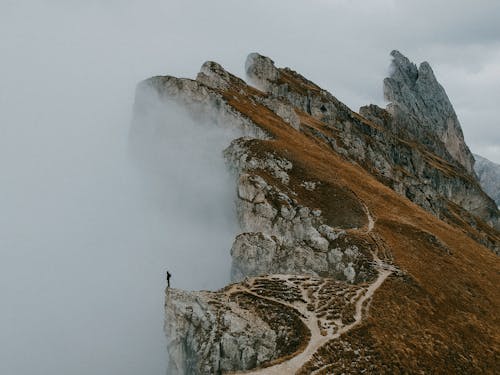 Фотография человека, стоящего на краю утеса