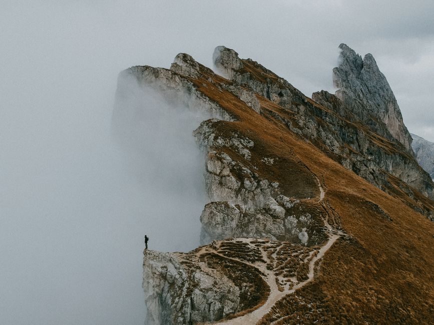 A solitary figure on the misty cliffs of the Dolomites in Italy, an epic autumn landscape.