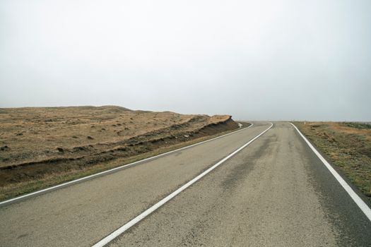 A solitary road traversing the barren Georgian landscape under a cloudy sky.