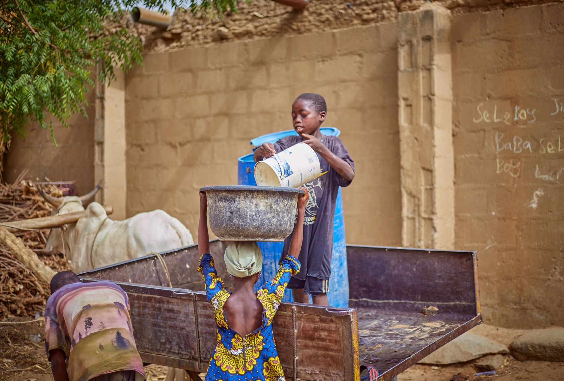 A child helps an adult with daily chores in a rural African setting.
