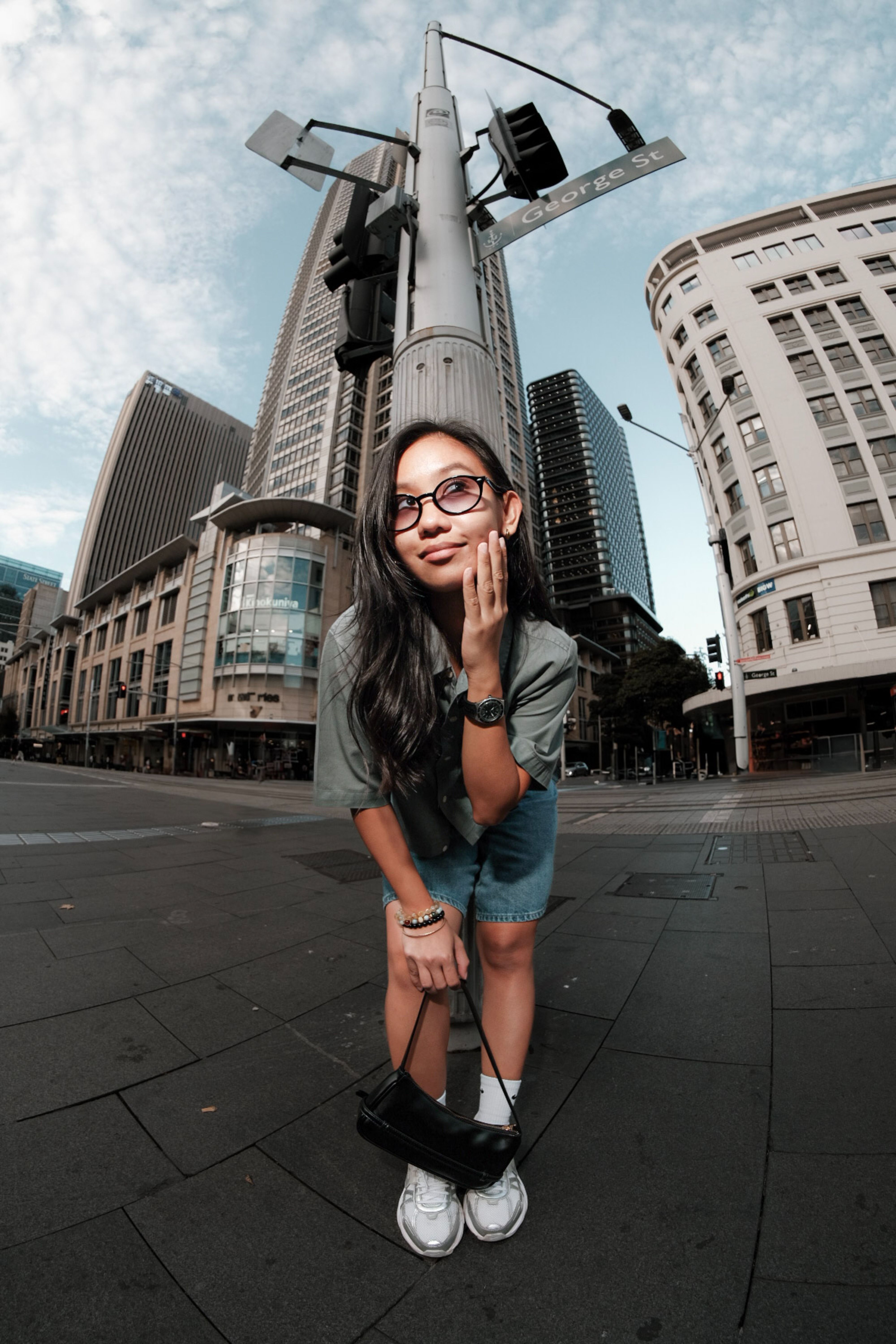 Young woman posing confidently in downtown Sydney with skyscrapers in the background.
