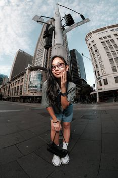 Young woman posing confidently in downtown Sydney with skyscrapers in the background.