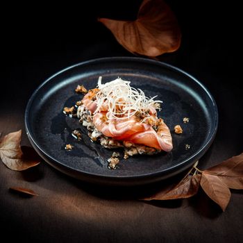 Delicious gourmet salmon sashimi dish elegantly presented on a dark plate.