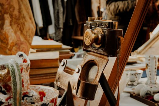 A classic vintage camera in a leather case displayed in an antique shop setting.