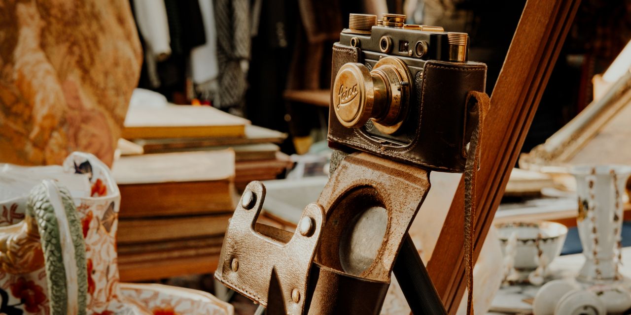 A classic vintage camera in a leather case displayed in an antique shop setting.
