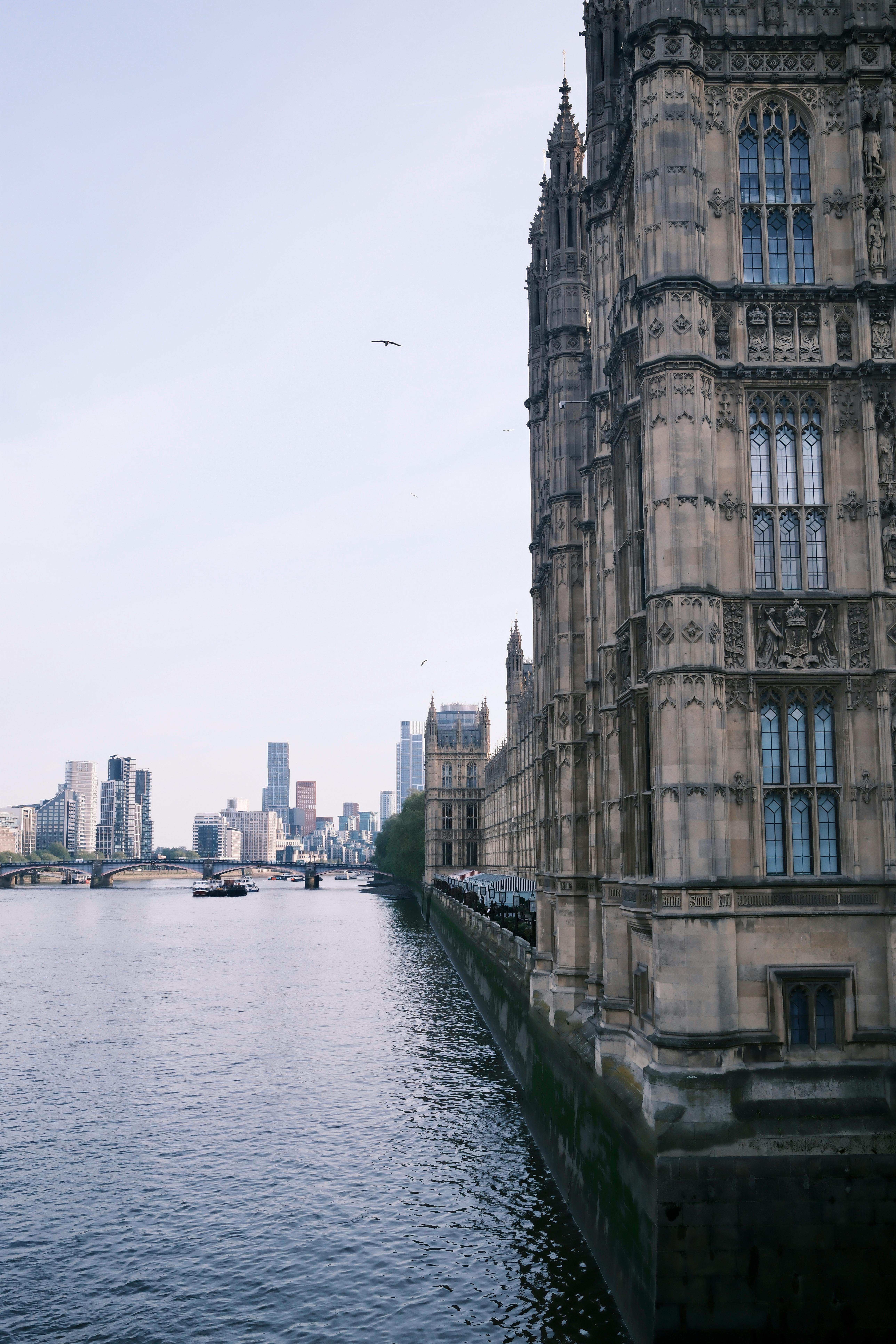 Historic Westminster architecture with London skyline view along the Thames River.