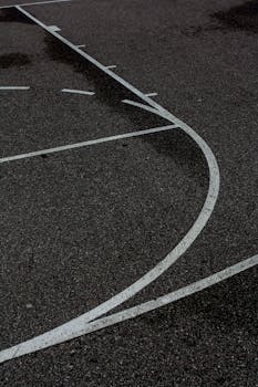 A moody night view of a wet outdoor basketball court.