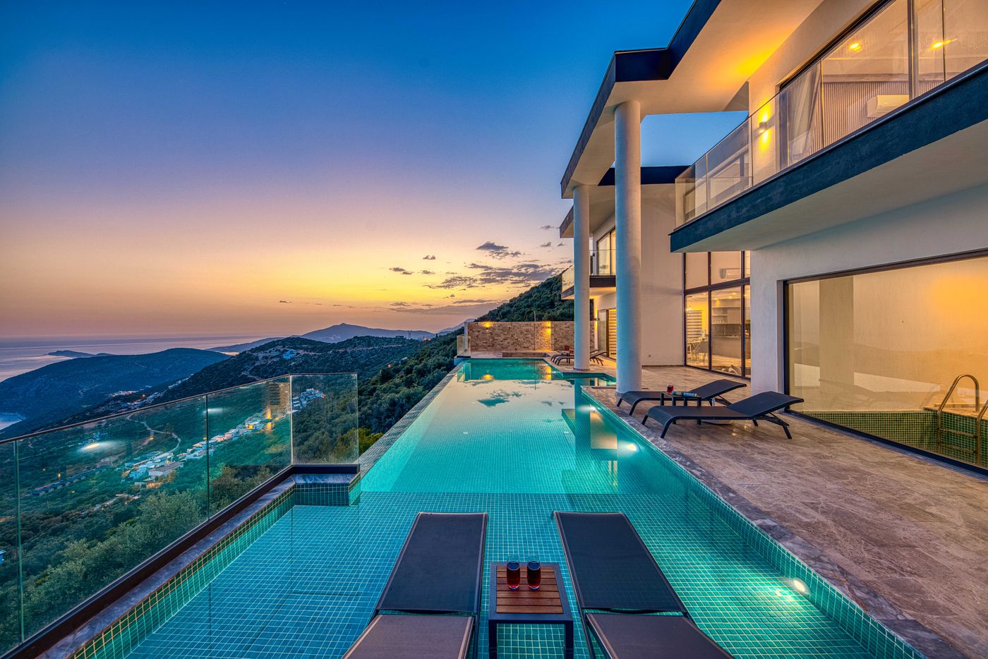 A luxury villa with an infinity pool overlooking the sea at sunset