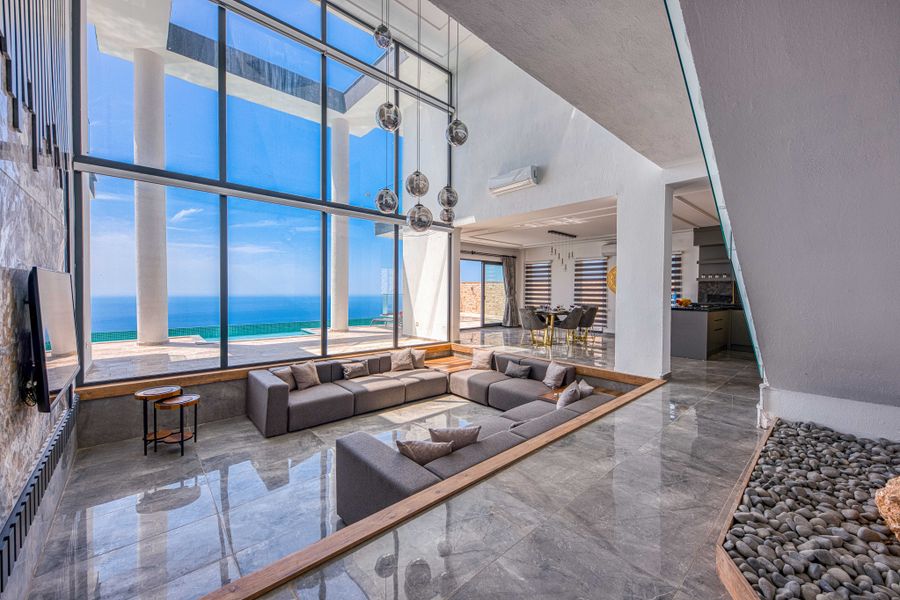 A living room with floor-to-ceiling glass and a sea view