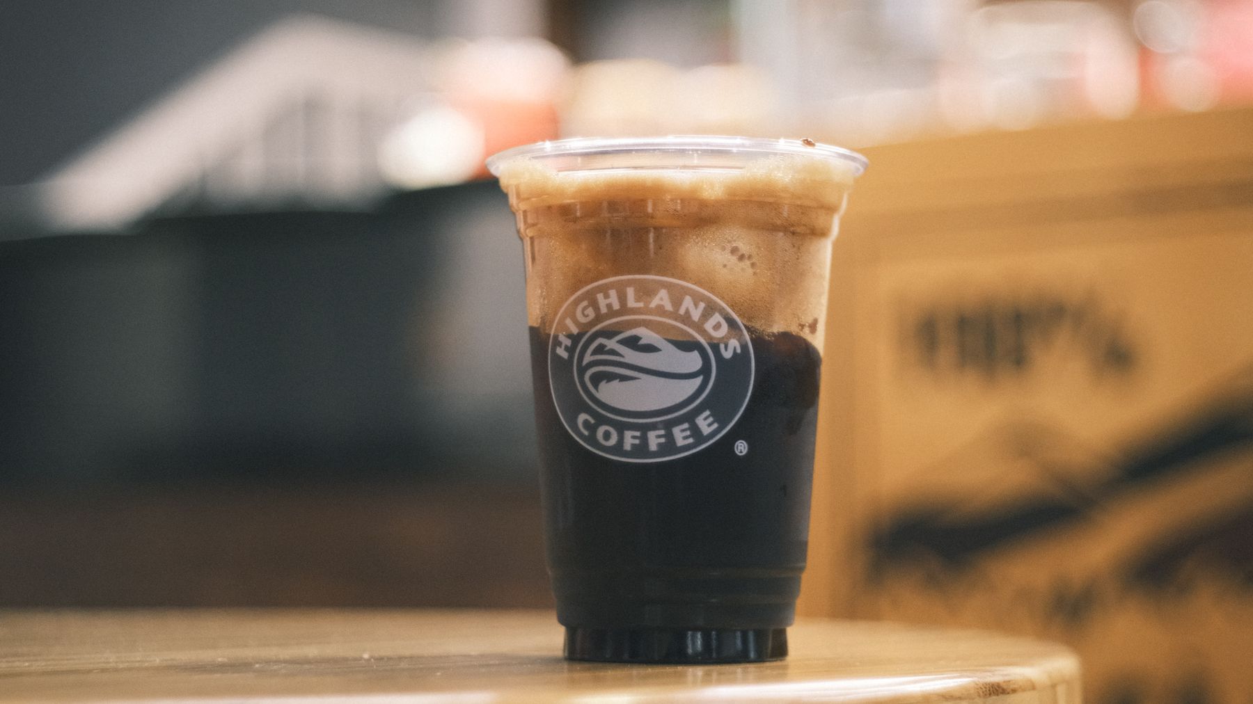 Close-up of Highlands Coffee cup with foam in modern cafe setting.