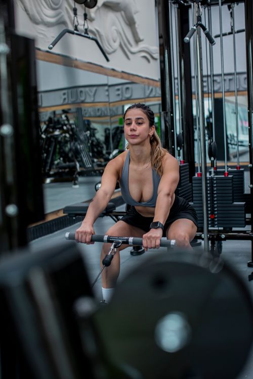 Free Focused woman working out on a rowing machine in a modern gym setting. Strength and determination. Stock Photo