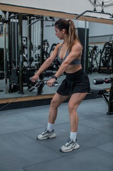 Female athlete working out with a cable machine at an indoor gym, showcasing strength and fitness.
