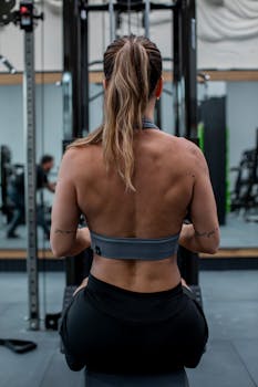 Back view of a female athlete exercising in a gym, focusing on her workout routine.