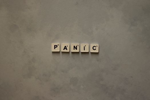 Scrabble tiles forming the word 'Panic' on a simple neutral background, symbolizing anxiety.