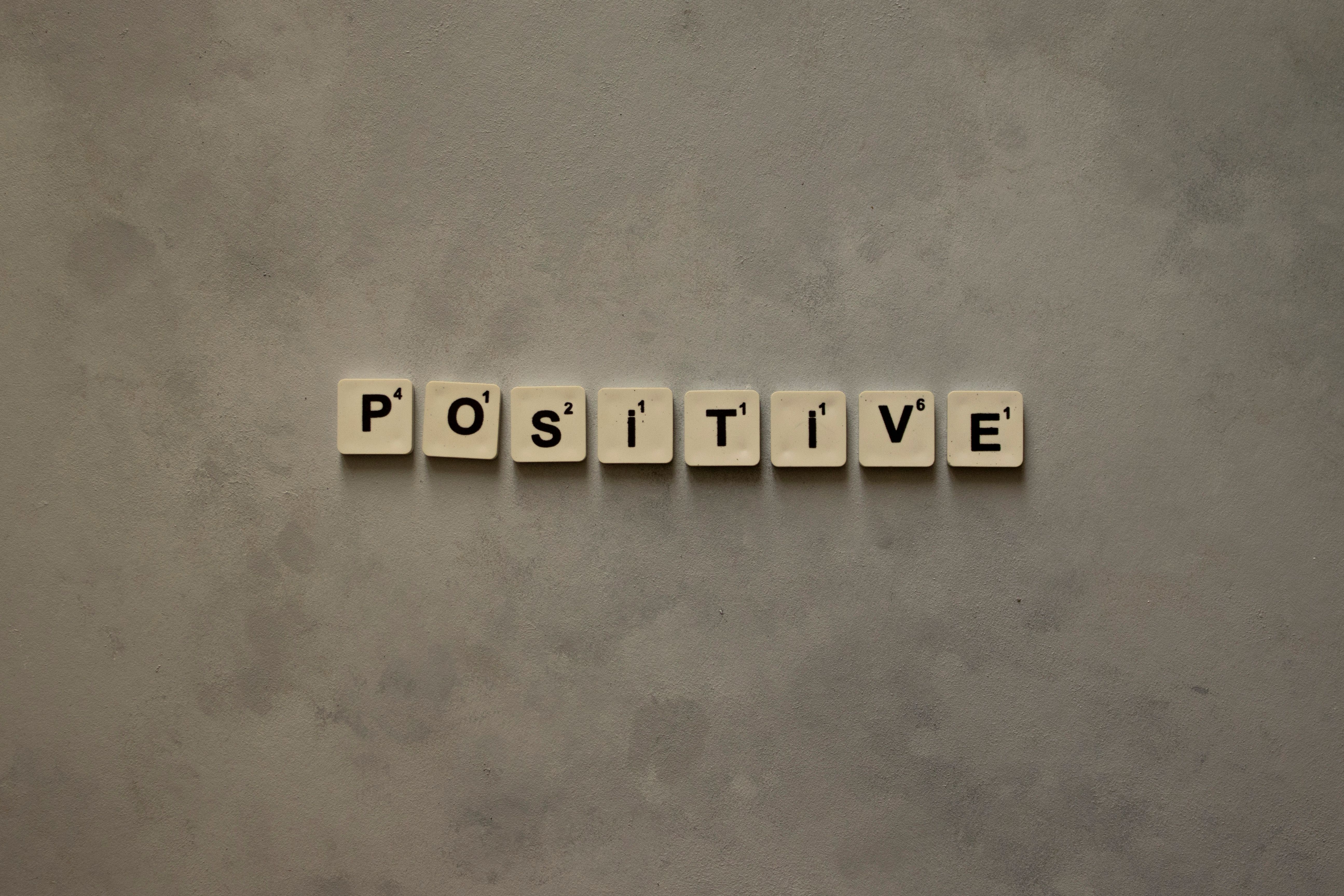 Scrabble tiles spelling 'Positive' on a textured surface, conveying optimism.