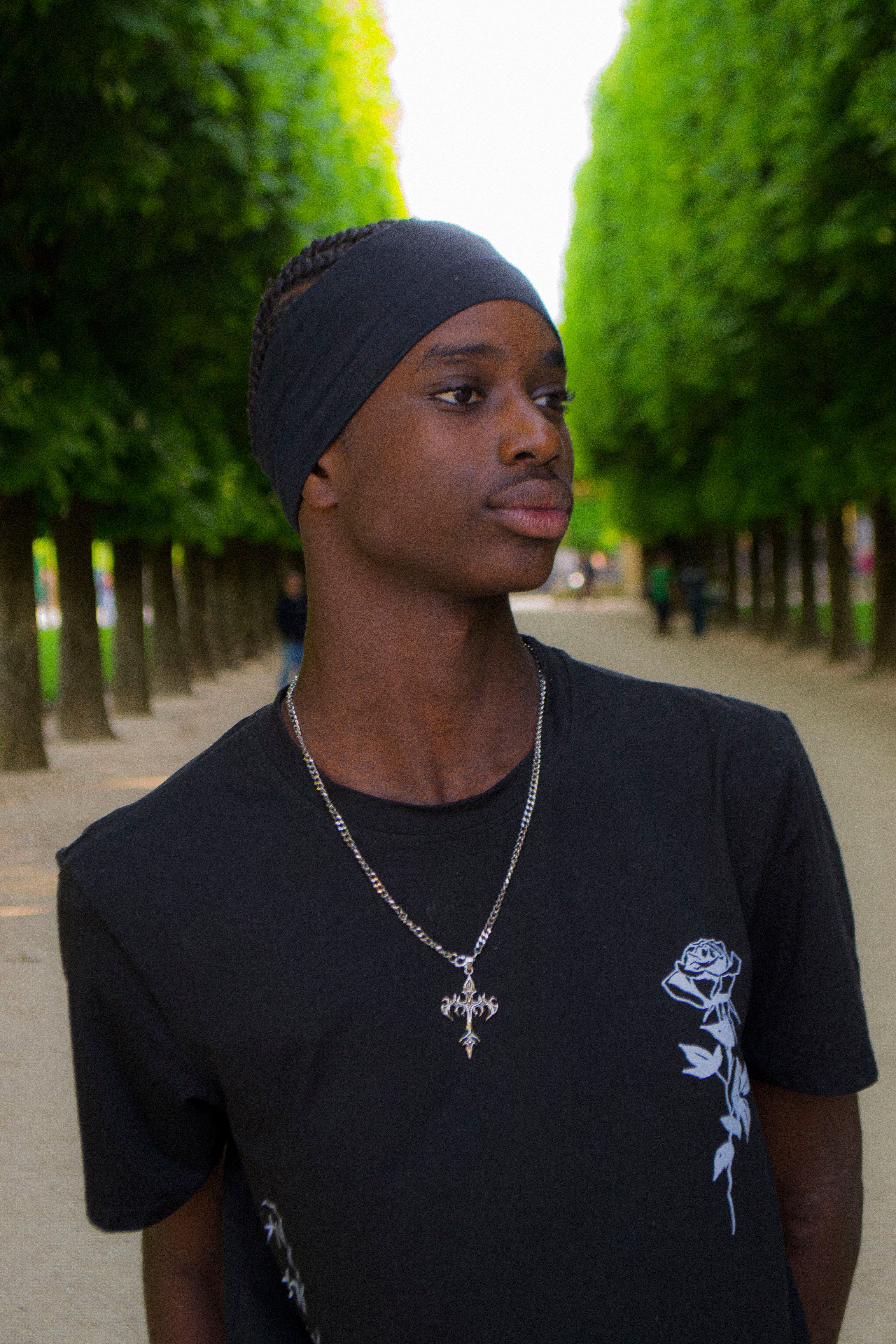 Portrait of a young man standing outdoors in a tree-lined park.