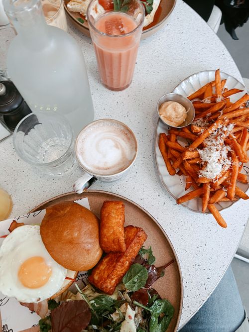 Free A delightful brunch setting featuring sweet potato fries, juice, and coffee on a white table. Stock Photo
