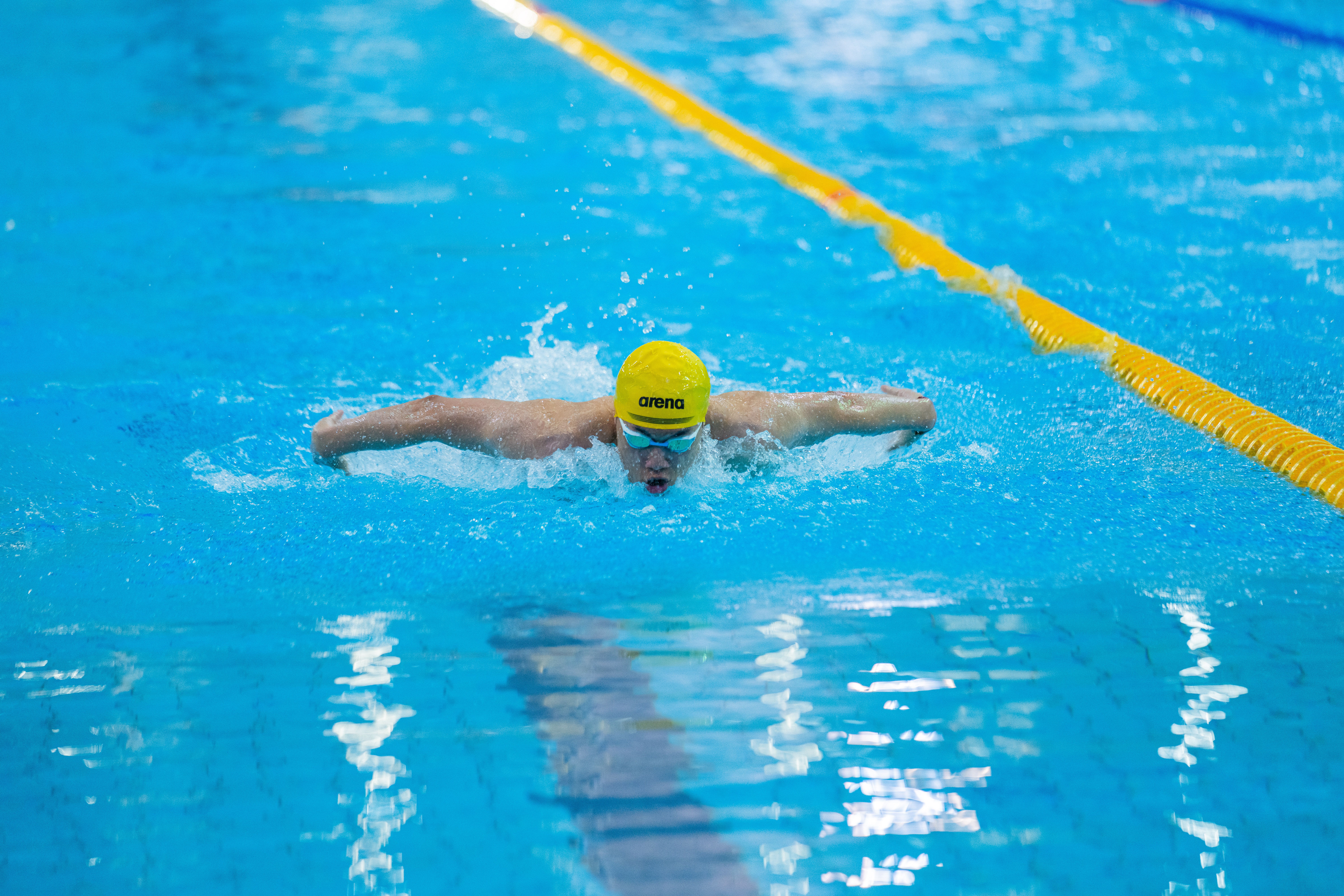 Swimmer in colorful cap doing butterfly stroke in pool competition