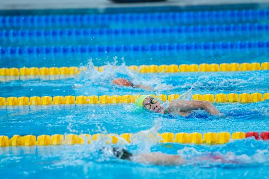 Action shot of competitive swimmers racing in a swimming pool during a daytime event.