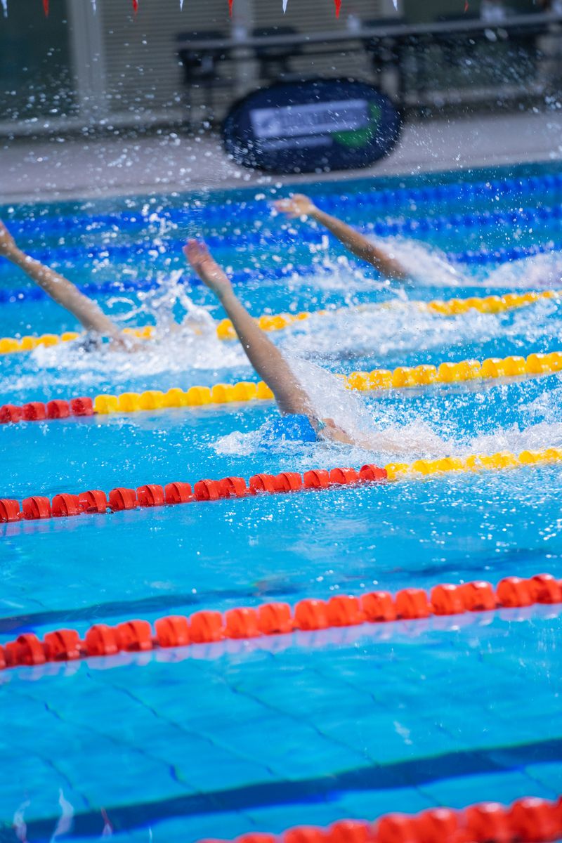 Swimmers competing in a professional backstroke race in a pool with vivid lane markers.