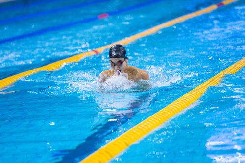 Free A focused adult male swimmer performing the breaststroke in an indoor swimming pool during the day. Stock Photo