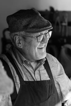 Cheerful senior artisan wearing an apron and cap in a workshop setting.