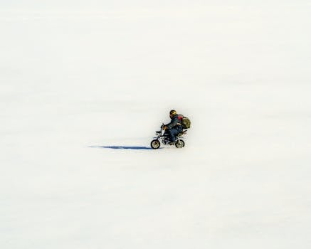 A lone motorcyclist traverses a vast snowy landscape in Kemi, Finland.