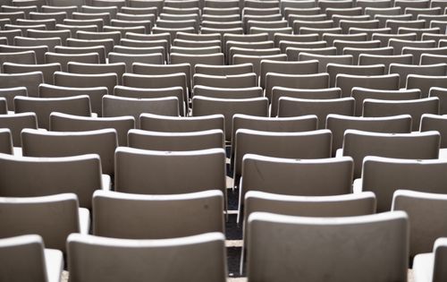 Free Symmetrical arrangement of white plastic chairs in an outdoor setting, awaiting an audience. Stock Photo
