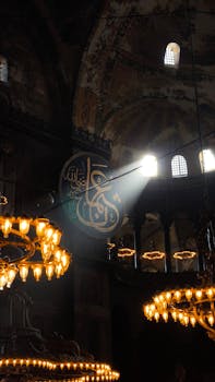 Sunlight streams through the dome of a historic Byzantine building, illuminating ornate chandeliers.